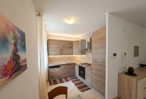 a small kitchen with wooden cabinets and a painting on the wall at a casa di LUCA in Capriate San Gervasio