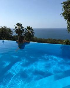 a woman in a swimming pool with blue water at Villa Vigie in Deshaies