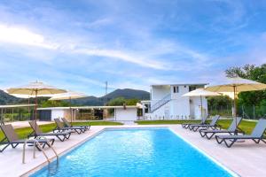 a pool with chairs and umbrellas next to a house at Villa Demetrious in Kondáraina