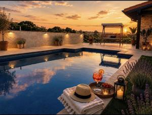 a pool with a hat and a table with a drink at La Carrera, villa moderna con piscina privada en Mogro Cantabria in Mogro