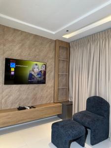 a living room with a chair and a tv on the wall at Greyfield Apartment Anex in Benin City