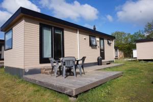 a house with a table and chairs on a deck at 't Veldhuisje 109 - naast het bos, honden toegestaan in Anloo