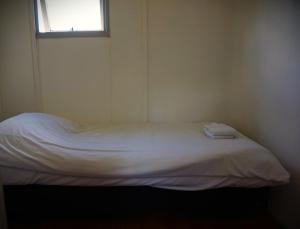 a white bed in a room with a window at 't Veldhuisje 109 - naast het bos, honden toegestaan in Anloo