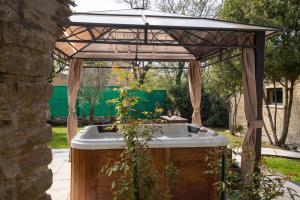 a gazebo with a bath tub in a garden at Ô Jacuzzi du Mazet in Murles