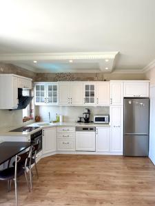 a kitchen with white cabinets and stainless steel appliances at Maison Edina - Cunda in Ayvalık