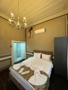 a bedroom with a bed with white sheets and a chandelier at Avlia Konakları in Edirne