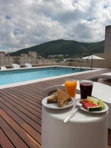 a table with a plate of food and drinks on a balcony at Hotel Alvarado Suites in Salta