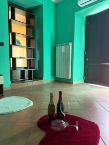 two bottles and two glasses on a rug in a room with green walls at Casa Lory in Posta Fibreno
