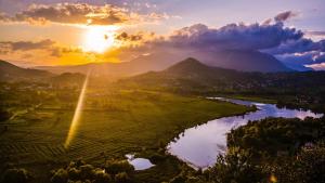 a sunset over a field with a river and mountains at Casa Lory in Posta Fibreno +12 photos