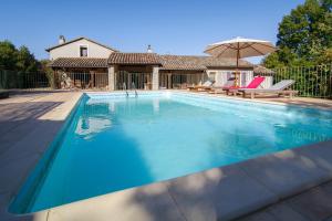 a swimming pool with an umbrella and a house at Gîte au Couchant à Caylus - Piscine - Jardin - 3 chambres - 8 personnes - 5 minutes du village médiéval in Caylus