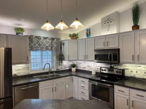 a kitchen with white cabinets and a sink and a microwave at Lake Melissa Cabin on the Commons in Detroit Lakes