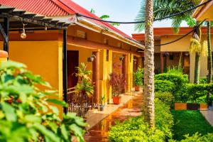a yellow house with palm trees in front of it at Palm Star Motel in Fort Portal