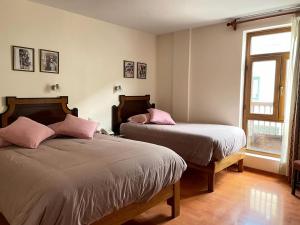 a bedroom with two beds and a window at Casa Elena in Cusco