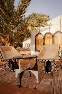 a table and a chair in front of a tent at Sahara Sky Luxury Camp in Merzouga