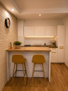 a kitchen with two bar stools and a counter at Liberty Deluxe Apartment Cosmopolis in Creţuleasca
