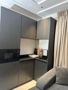 a kitchen with grey cabinets and a couch in a room at Greyfield Apartment Anex in Benin City
