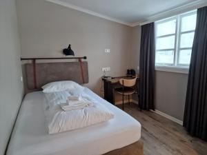 a bedroom with a bed and a desk and a window at Gistihúsið - Lake Hotel Egilsstadir in Egilsstaðir