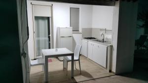 a small kitchen with a table and a white refrigerator at Giardino dei Baroni house in Marina di Mancaversa