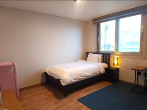 a small bedroom with a bed and a window at Sea Star Hostel in Yeosu