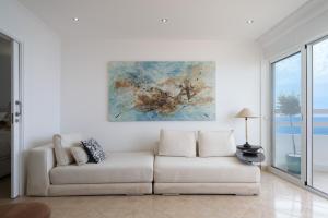 a white couch in a living room with a painting at Lighthouse - Exclusive Sea view 180º, pool, parking in Portimão