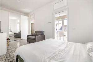 a white bedroom with a bed and a chair at Da Marilena in Sorso