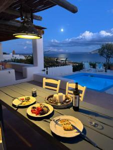 a table with plates of food and a bottle of wine at Pambelos Lodge in Koufonisia