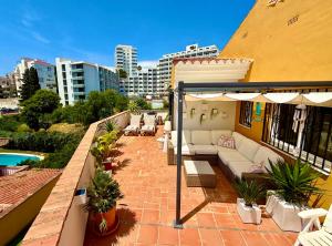 an outdoor patio with a couch and an umbrella at Penthouse - Beach - Sea View - Pool - 40 sqm Private Terrace - One Bedroom - Sleeping Alcove in Benalmádena
