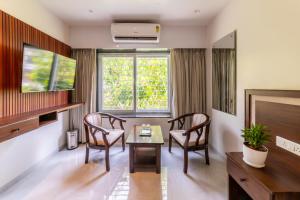 a living room with a table and chairs and a tv at Lumina Stays-Modern Luxury Rooms, Near NAD in Visakhapatnam