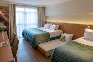 a hotel room with two beds and a window at Bourbon Convention Hotel Santos in Santos