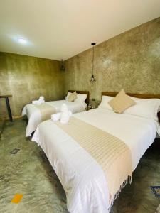 ein Schlafzimmer mit drei Betten mit weißer Bettwäsche in der Unterkunft Hotel Casa Grangelo in Atlixco