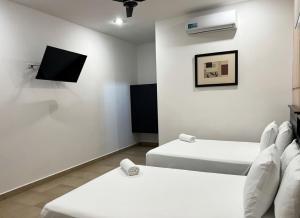 a room with two beds and a flat screen tv at Hotel Zibahun in Valladolid