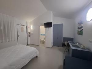 a white bedroom with a bed and a bathroom at Le Casette Del Mare in Crotone