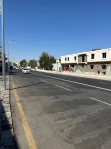 an empty street with a white car driving down the road at MUXSIN s in Bukhara