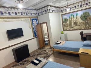 a hotel room with a bed and a tv and a room at MUXSIN s in Bukhara