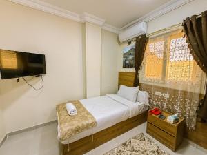 a small bedroom with a bed and a television at Nigmt Siwa Hotel in Siwa