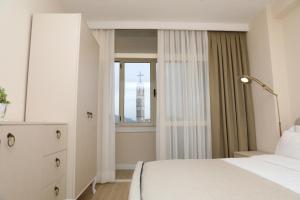 a bedroom with a white bed and a window at City Views Apartment in Shkodër