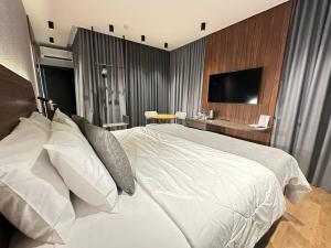 a bedroom with a white bed and a television at Zallon Hotel Executivo - Late Checkout Cortesia as 15hs aos DOMINGOS in Lajeado