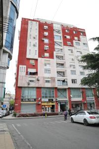 a tall red building with a car parked in front of it at City Views Apartment in Shkodër