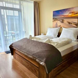ein Bett in einem Zimmer mit einem großen Fenster in der Unterkunft Südwind Apartment Nr 05 - FeWo Usedom, strandnah, Schwimmbad, Sauna, Parkplatz, WLAN, und Balkon in Zempin + 20 Fotos