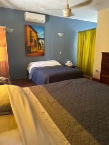 ein Schlafzimmer mit zwei Betten und einem Gemälde an der Wand in der Unterkunft Casa de la Alegria 2 apartments in Mazatlán