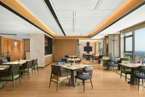 a dining room with tables and chairs and windows at Four Points by Sheraton Shanwei Lufeng in Shanwei