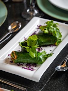 a white plate with two vegetables on a table at Mansión del Cobre Hotel Boutique in Los Mochis