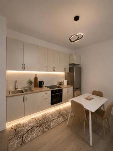 a kitchen with white cabinets and a table with chairs at ARMAS Stay in Kamëz
