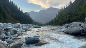a river with rocks and trees on a mountain at Aroha Living in Bandal