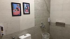 a bathroom with two pictures on the wall and a toilet at Aroha Living in Bandal