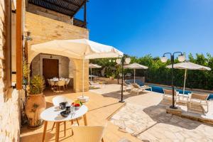 a patio with tables and umbrellas and a pool at Villa Marcos Chara in Astérion