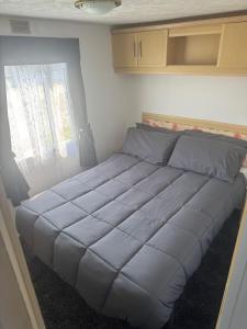 a large bed in a small room with a window at Kathy's Warden springs caravan in Leysdown-on-Sea