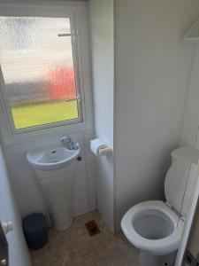 a bathroom with a toilet and a window at Kathy's Warden springs caravan in Leysdown-on-Sea +9 photos