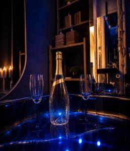 a bottle of wine sitting on a table with three wine glasses at JACUZZI & SAUNA Apartament Warszawa Wola in Warsaw