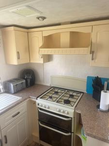 a kitchen with white cabinets and a stove top oven at Kathy's Warden springs caravan in Leysdown-on-Sea